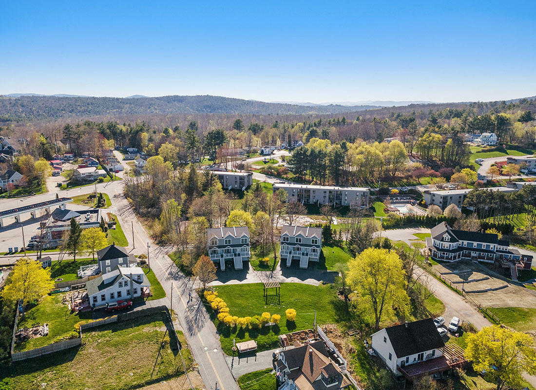 Insurance Solutions - Aerial View of a Residential Neighborhood with Homes Surrounded by Trees in New Hampshire in the Late Fall with Views of Mountains in the Background