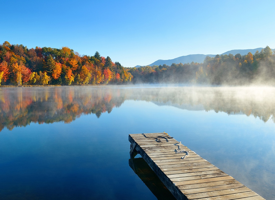 We Are Independent - View of a Long Wooden Dock on a Quiet River in the Countryside with Colorful Fall Trees on a Foggy Morning with a Clear Blue Sky